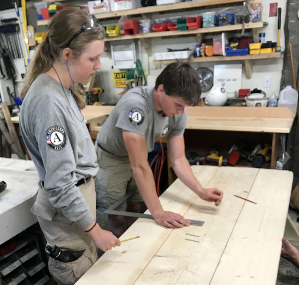 AmeriCorps volunteers mark a picnic table.
