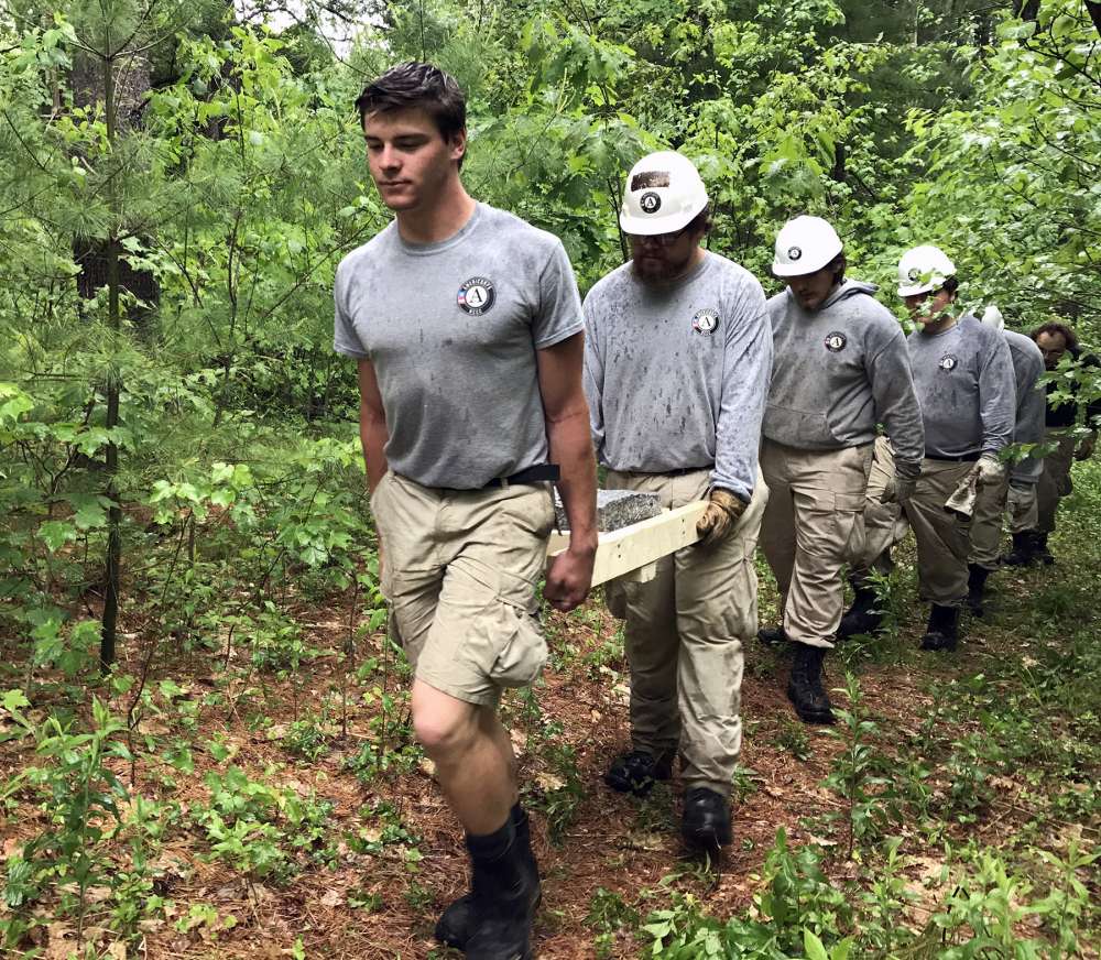 AmeriCorps volunteers haul granite for a bench at Ghost Meadow.