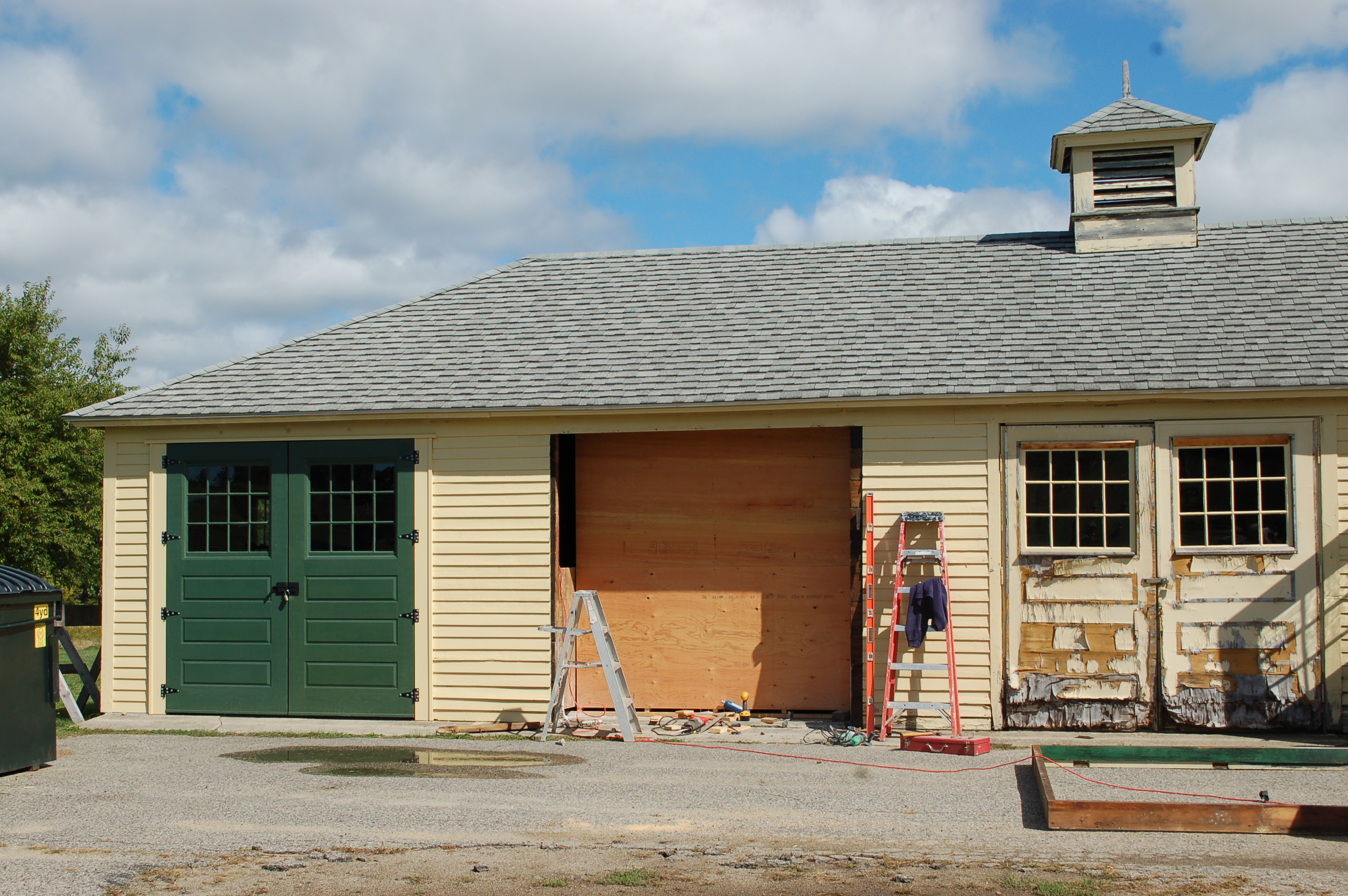 Garage door rebuilds in progress: One replaced, one down for work, and one showing wear.