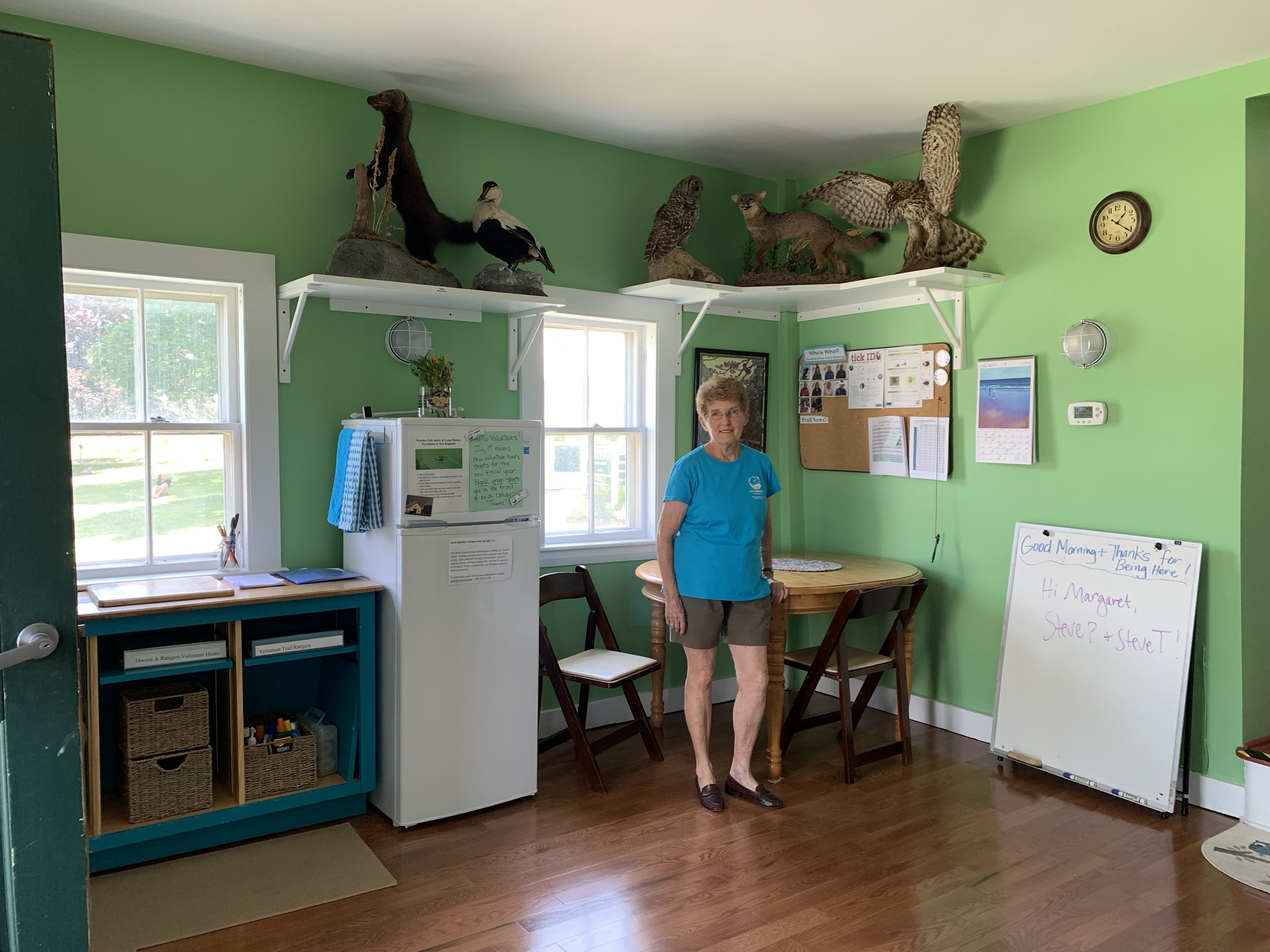 Volunteer Carolyn Broad and the walls she painted "picnic" green for the docent room remodel. Photo by Amy Maden.